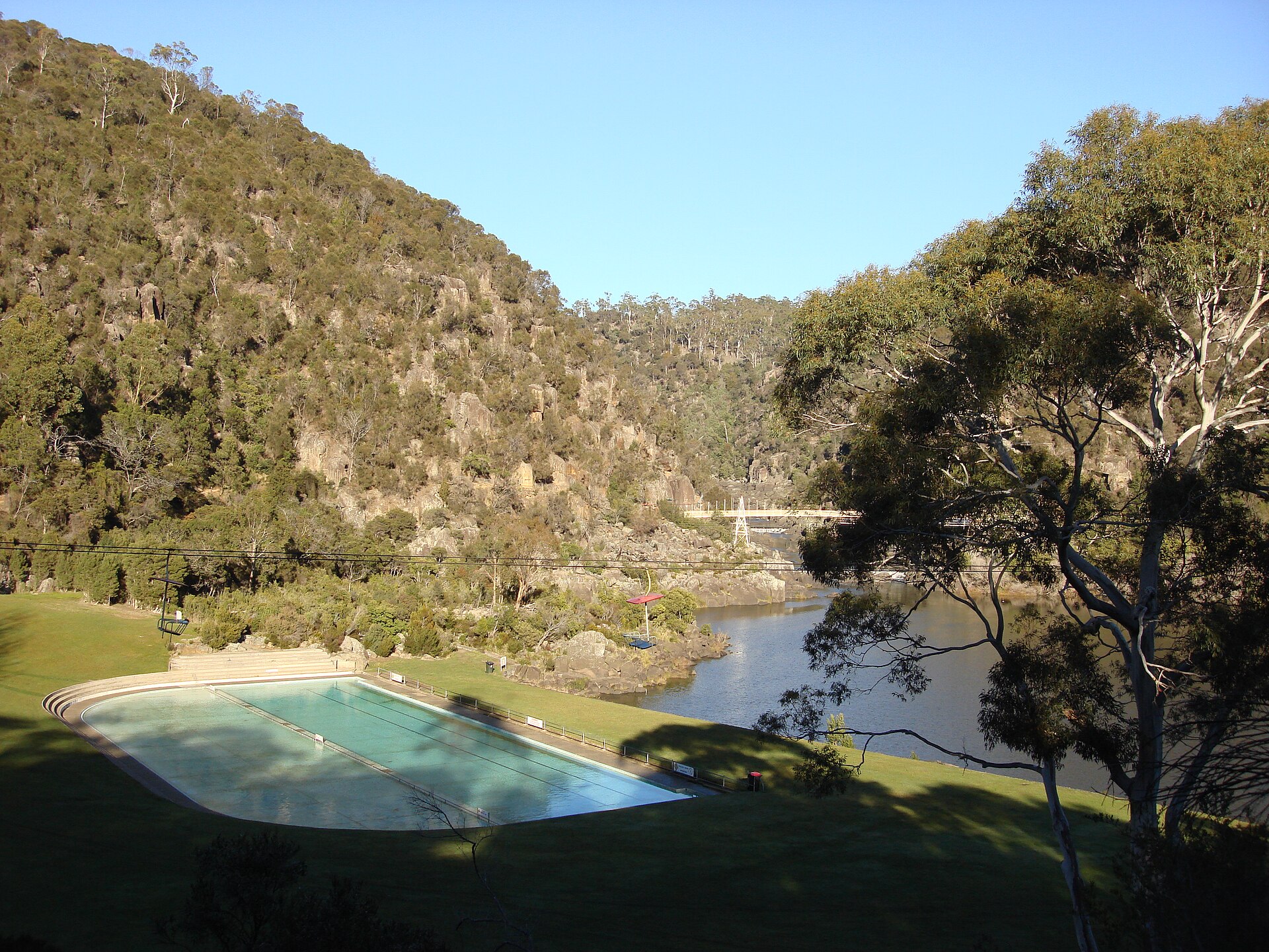 The Cataract Gorge is a river gorge in northern Tasmania, near Launceston, and is one of the region's premier tourist attractions. A pathway, known as the King’s Bridge-Cataract Walk, and originally built by volunteers in the 1890s, runs along the north bank of the Cataract Gorge, and is a popular tourist destination. The chairlift crossing the Gorge is the longest single span chairlift in the world, with the longest span being 308m (924 ft). The chairlift, built in 1972, has a total span of 457m. Before the Hydro Dam was built in the 1950's upstream, flood waters could rise up as high as 12 metres. In the past, there was a power station at Duck Reach, about 2.5 kilometres from the suspension bridge. It was washed away in the floods of 1929, rebuilt and then decommissioned when the new Hydro Dam was finished in 1955. The building is now an interpretive museum. The First Basin on the southern side features a swimming pool and an open area surrounded by bushland. At the lower end of the Gorge, the South Esk spills into the Tamar River going under Kings Bridge on the way. This was the only bridge leading north out of the city for nearly 100 years. [Wikipedia.org]