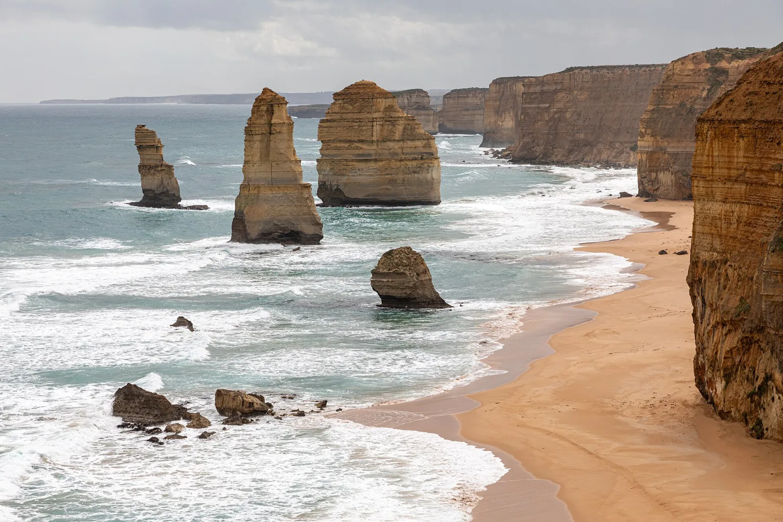 Twelve Apostles at Port Campbell National Park, Princetown, Victoria, AustraliaPort Campbell National Park is located on the south coast of Victoria along the Great Ocean Road and protects a spectacular coastal landscape of limestone, cliffs, caves, and natural bridges.Its geological formation dates back millions of years: over thousands of years, layers of limestone and shells formed caves, gateways, and towers, which were repeatedly eroded by the Southern Ocean. The coast also served as a habitat for indigenous groups in the region, including the Wergaia and Eastern Maar communities. From the 1950s/60s onwards, the area was designated a protected area to preserve its exceptional geology, wildlife, and flora and to manage visitor flows in a sensible manner.Special features include the famous limestone cliffs, narrow passages, natural bridges, and steep cliffs; highlights such as the Twelve Apostles, Loch Ard Gorge, and other coastal formations attract many visitors each year. The sea is home to seals, seabirds, and rich marine fauna, while the rocky shores also support maritime flora. Hiking trails, lookout points, and boat tours offer insights into geology, geomorphology, and coastal protection—a harmonious combination of natural wonders and historical perspective.